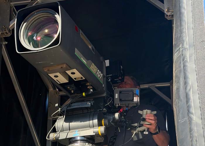 Camera operator running 101x box lens at live sporting event or concert